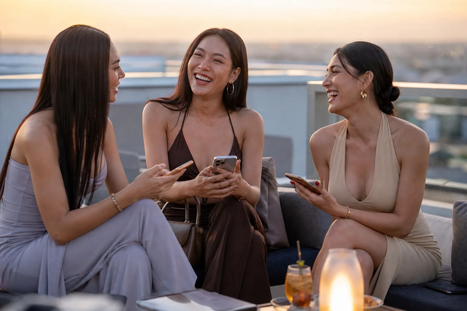 Three trans women friends talking on a rooftop terrace at golden hour